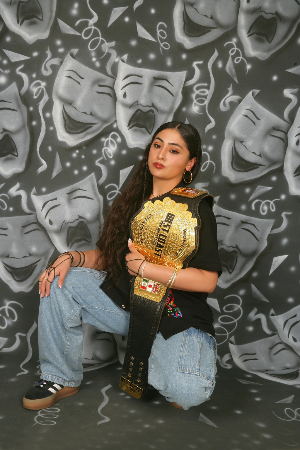 Person holding a championship belt against a background of theatrical masks