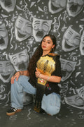 Person holding a championship belt against a background of theatrical masks
